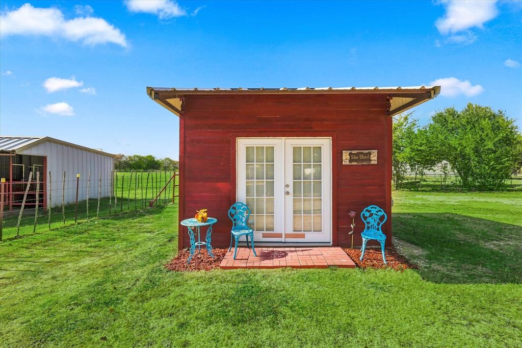 5855 Ge Horton Road Justin, TX 76247 - Photo 22 of 34 Red-sided auxiliary structure with a pitched roof, double glass-paneled entry doors, and a brick-paved patio area