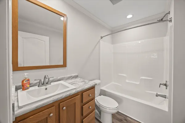 a bathroom with a bathtub shower sink vanity mirror and toilet