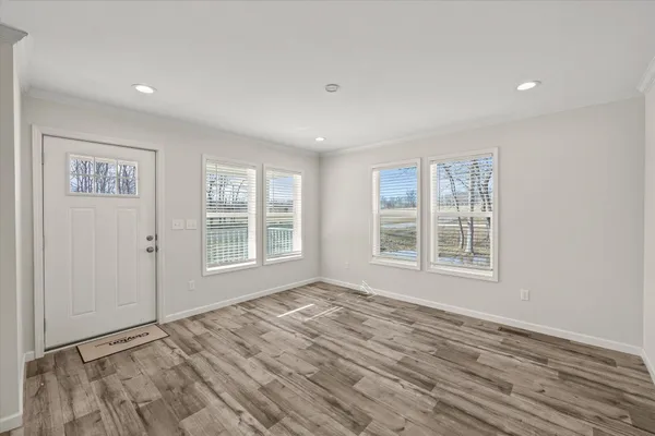 a view of an empty room with a window and wooden floor