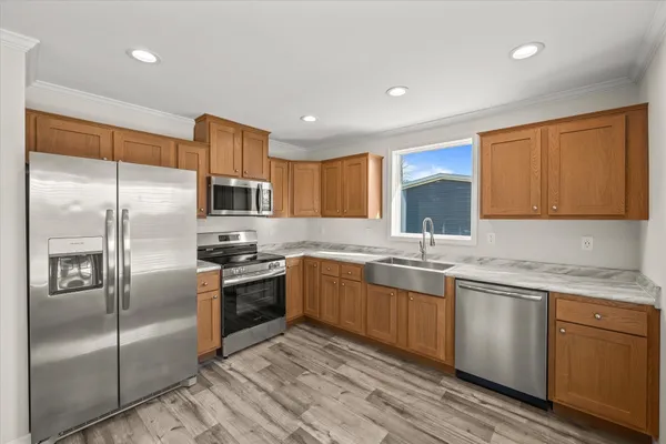 a kitchen with stainless steel appliances granite countertop a sink a stove a refrigerator and island with wooden floor