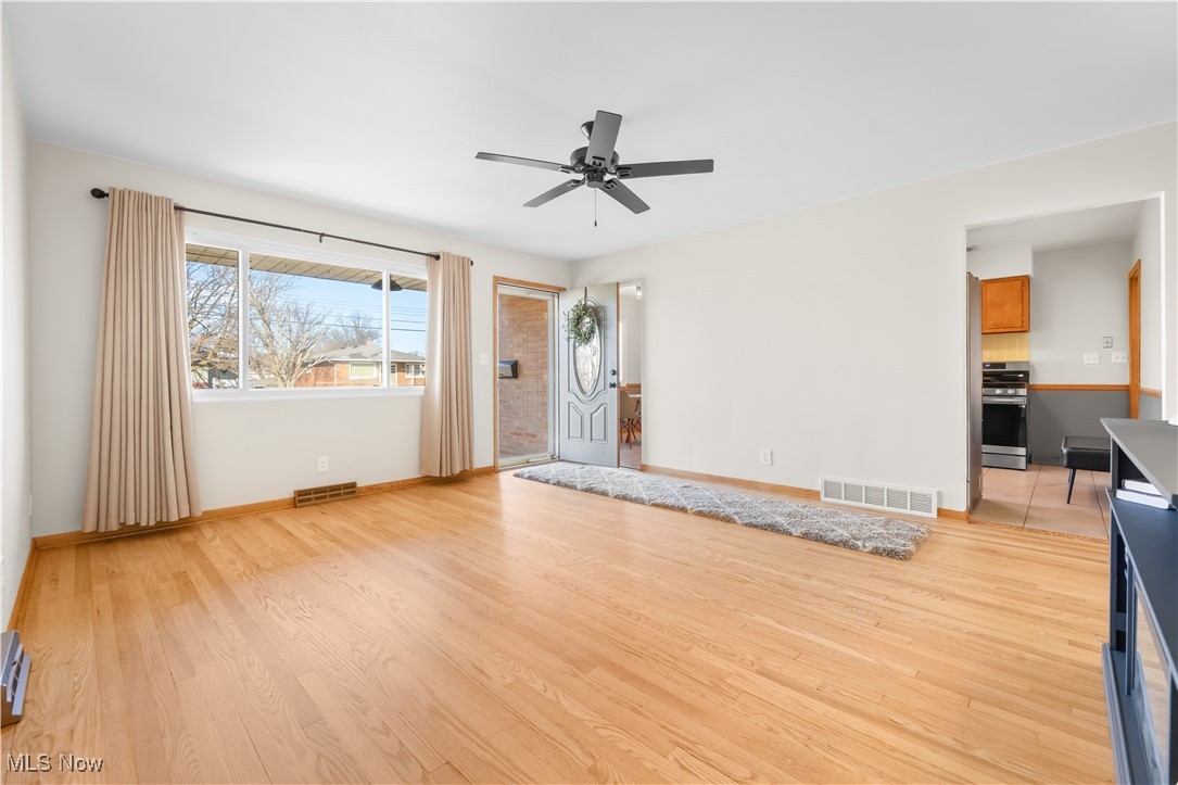 615 Ingalls Road Akron, OH 44312 - Photo 7 of 50 Unfurnished living room with ceiling fan, light wood finished floors, visible vents, and baseboards