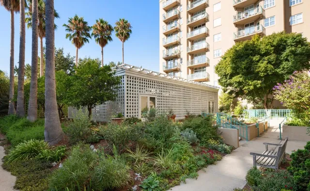 a front view of a building with a garden and trees