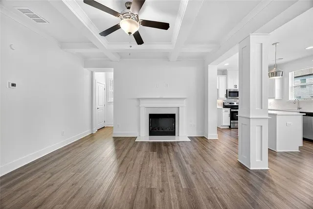 an empty room with wooden floor a ceiling fan a fireplace and windows