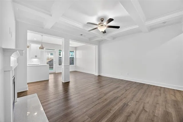 a view of an empty room with wooden floor and a ceiling fan