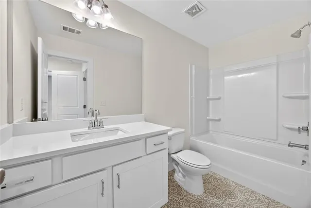 a bathroom with a granite countertop toilet a sink and a mirror