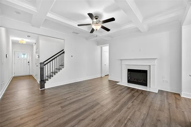 an empty room with wooden floor a ceiling fan a fireplace and windows
