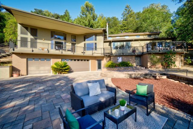 a view of a patio with couches table and chairs with wooden floor and fence