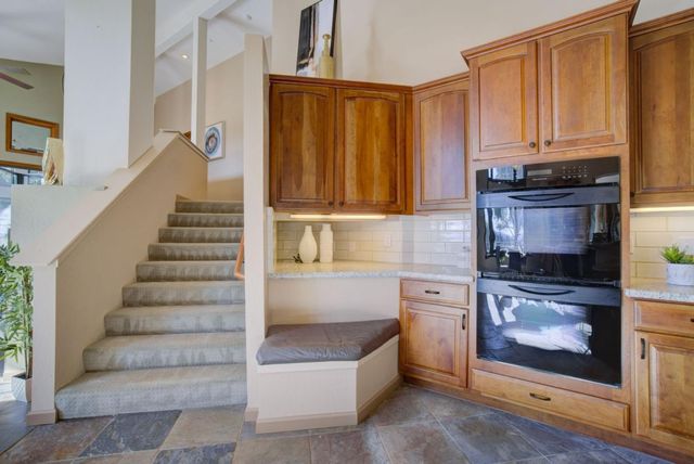 a dining hall with stainless steel appliances granite countertop a kitchen island a stove a sink a dining table and chairs with wooden floor