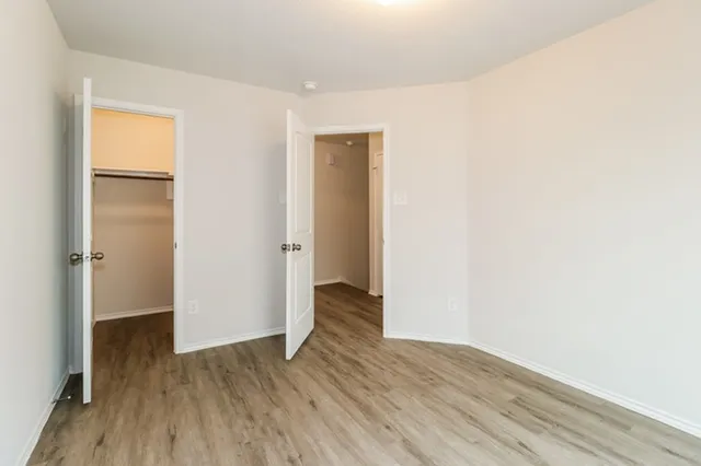 a view of an empty room with wooden floor and closet