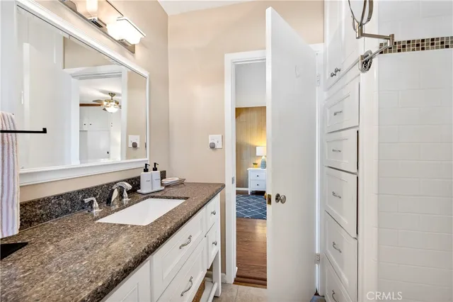 a bathroom with a granite countertop sink two mirror and a shower