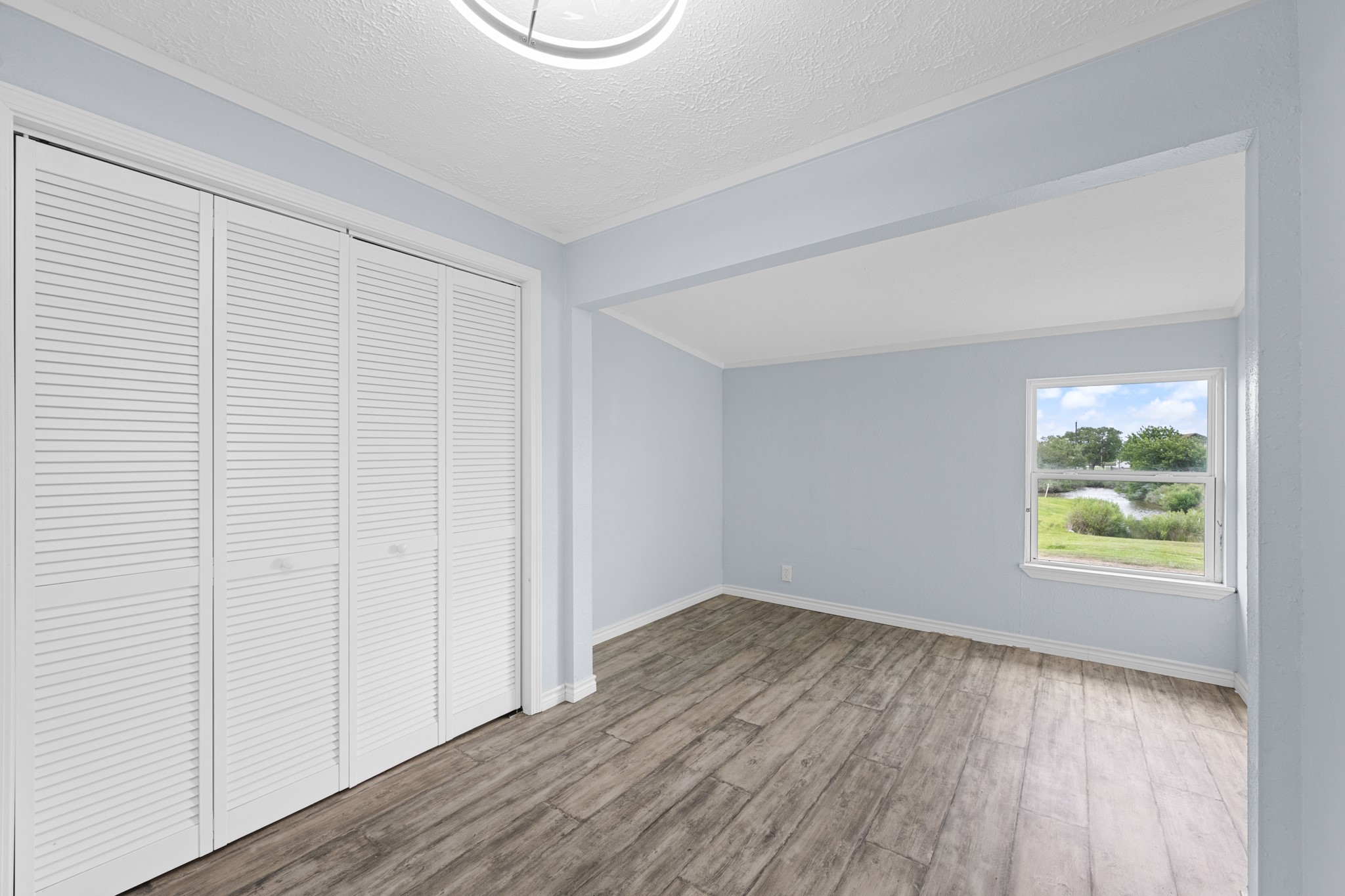 2534 Bastrop Angleton, TX 77515 - Photo 18 of 50 Spacious primary bedroom featuring updated wood-look flooring, soft neutral finishes, and a large window with peaceful outdoor views. Generous closet storage and a flexible layout create a comfortable private retreat filled with natural light.