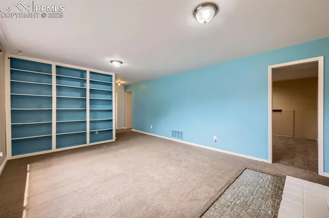 a view of an empty room with a fireplace and cabinet