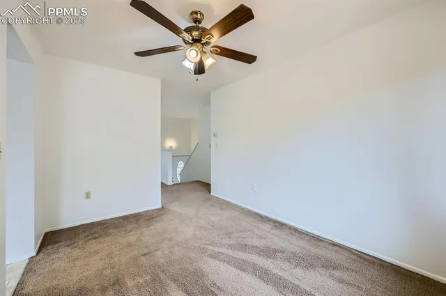 an empty room with a chandelier fan and a ceiling fan