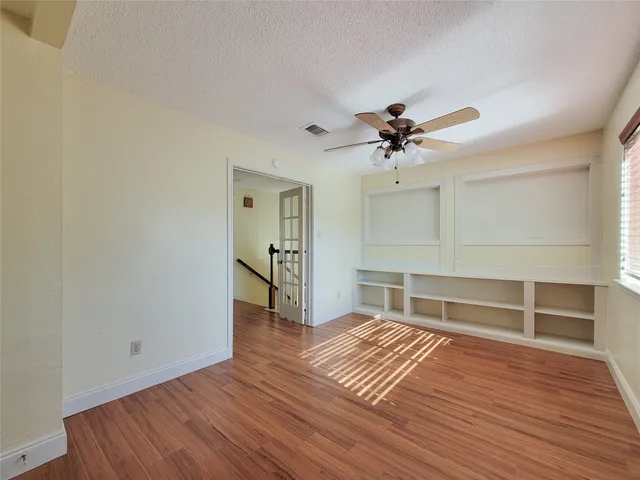 a view of empty room with wooden floor and fan