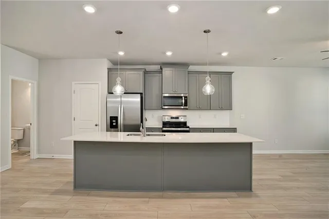 a large white kitchen with kitchen island a sink wooden floor and stainless steel appliances