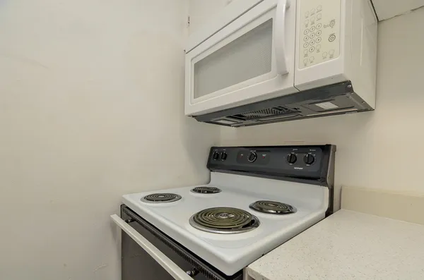a kitchen with a stove and a microwave with white cabinet
