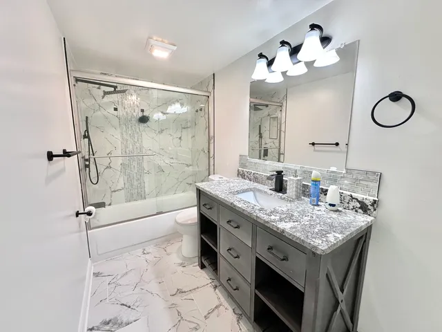 a bathroom with a granite countertop sink a large mirror and a shower