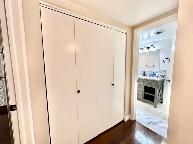 a view of a hallway with wooden floor and a bathroom
