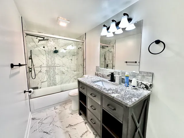 a bathroom with a granite countertop sink mirror and a bath tub