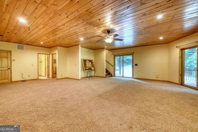 a view of a room with wooden floor and bench next to a yard