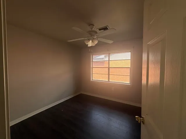 an empty room with a window and a ceiling fan