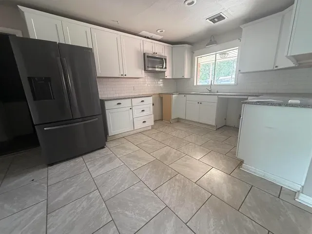 a kitchen with a refrigerator sink and cabinets
