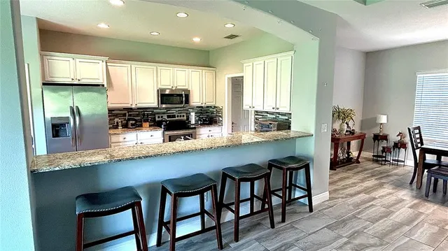 a kitchen with stainless steel appliances granite countertop a table chairs sink and cabinets