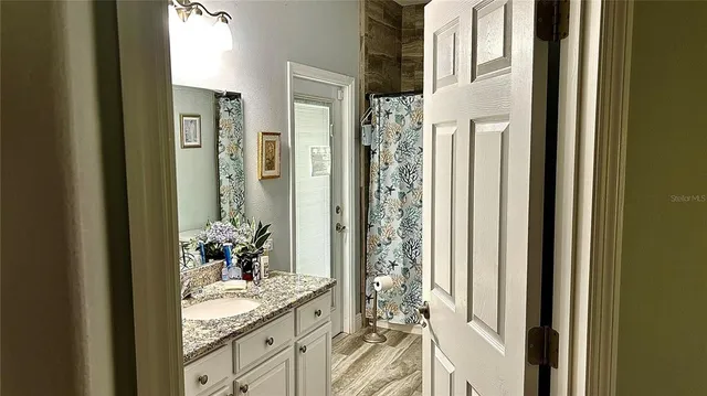 a bath room with a granite countertop shower and a mirror