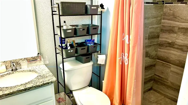 a bathroom with a granite countertop toilet and a sink