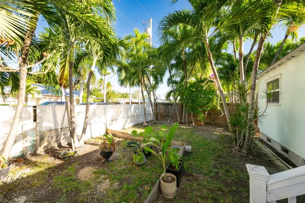 a backyard of a house with table and chairs potted plants and large tree