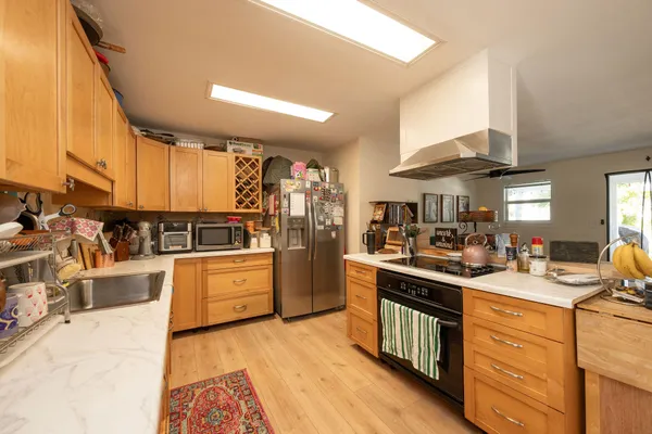 a kitchen with stainless steel appliances granite countertop a stove a sink dishwasher and a refrigerator with wooden cabinets