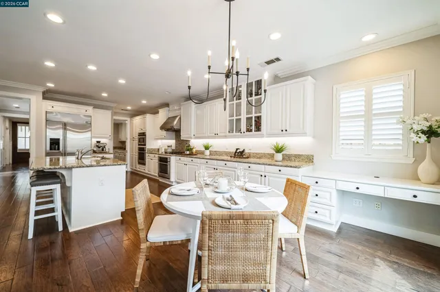 a kitchen with a dining table chairs wooden floor appliances and cabinets