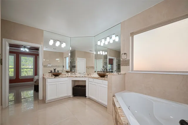 an empty room with wooden floor chandelier fan and windows