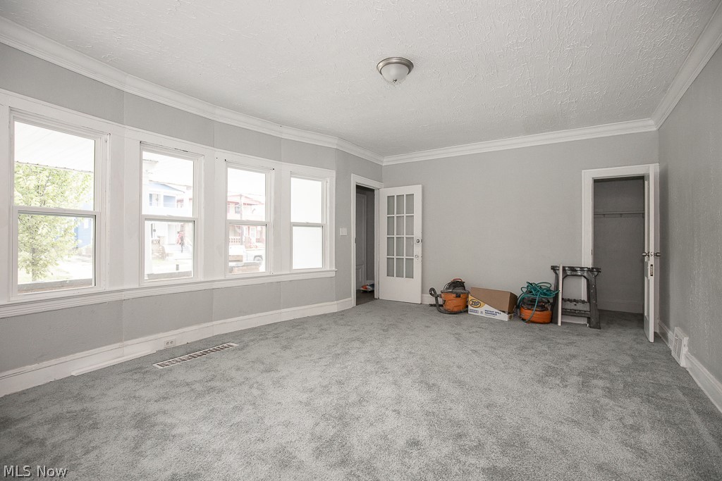 1000 Eddy Road Cleveland, OH 44108 - Photo 5 of 38 Empty room featuring a textured ceiling, crown molding, and carpet flooring
