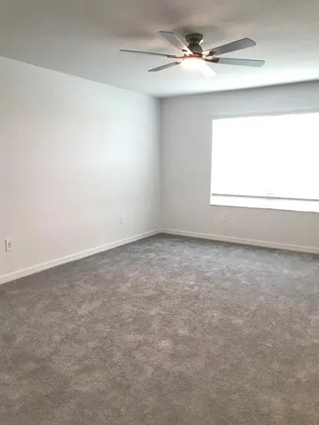 an empty room with a window and a ceiling fan