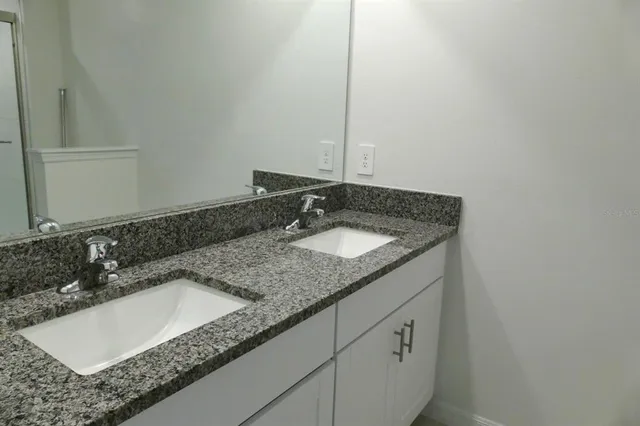 a bathroom with a granite countertop sink and a mirror