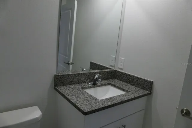 a bathroom with a granite countertop sink and a mirror