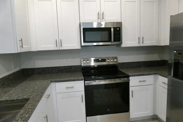 a kitchen with stainless steel appliances granite countertop a stove a microwave and oven