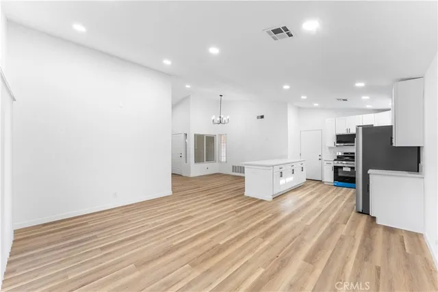 a large white kitchen with kitchen island a sink stainless steel appliances and cabinets