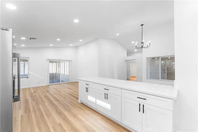 a view of a kitchen with kitchen island a sink wooden floor and a chandelier