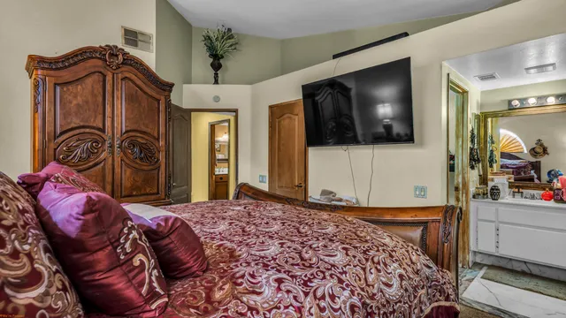 a bedroom with a bed a flat screen tv and dresser