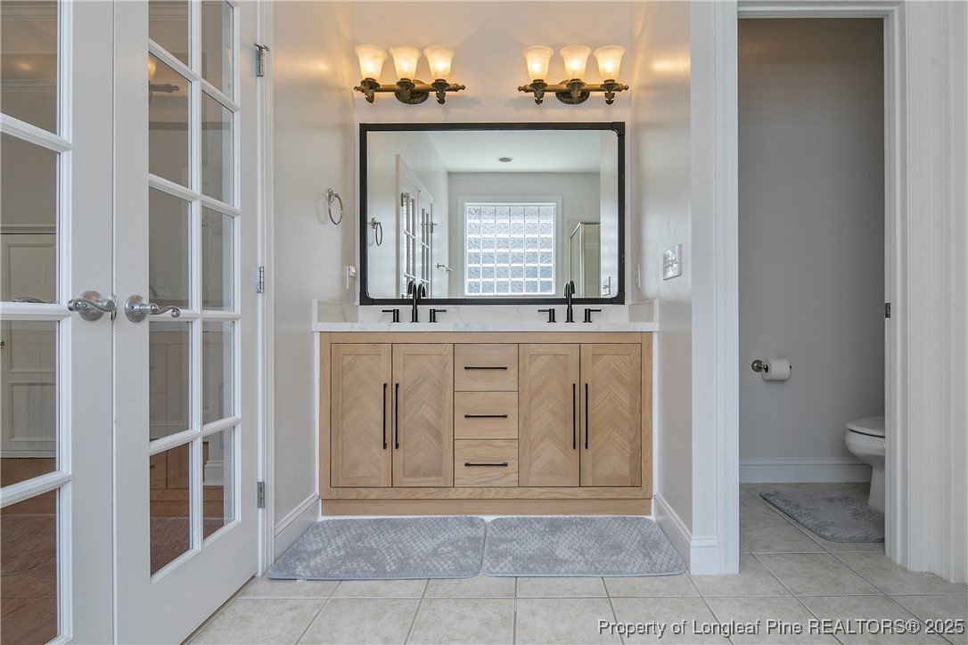 533 Falling Water Road Spring Lake, NC 28390 - Photo 30 of 50 a bathroom with a granite countertop sink a toilet and a mirror