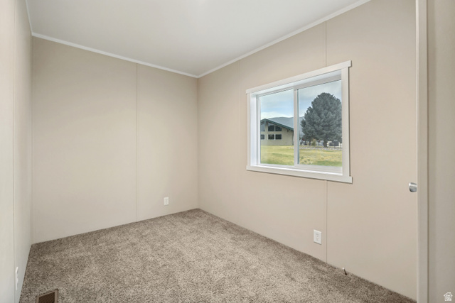 142 Cushing Way Layton, UT 84041 - Photo 7 of 15 Window with white trim framing distant mountains and a mature tree, complemented by neutral wall paneling and textured carpeting