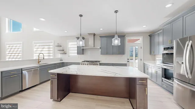 a kitchen with stainless steel appliances kitchen island a sink a stove a refrigerator and cabinets