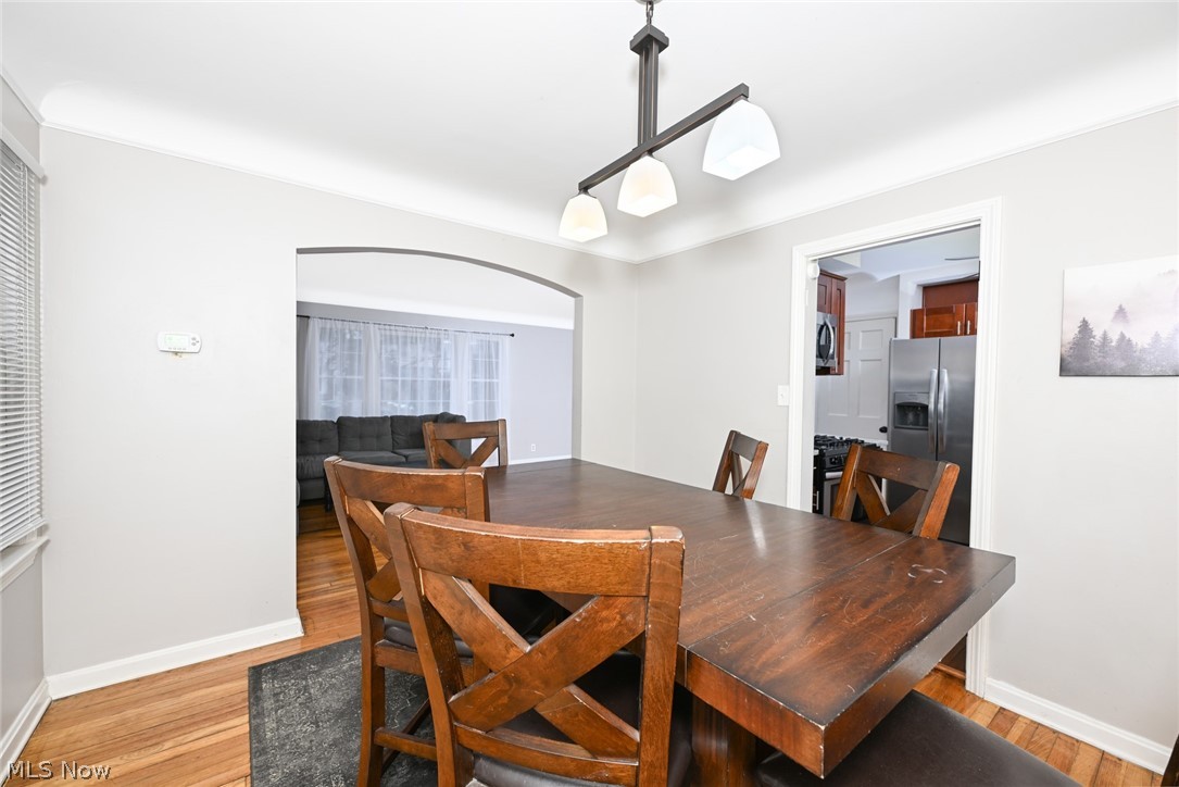 3699 Bainbridge Road Cleveland Heights, OH 44118 - Photo 10 of 37 Dining area featuring wood-finish flooring, a contemporary ceiling light fixture, and an arched doorway opening to another room