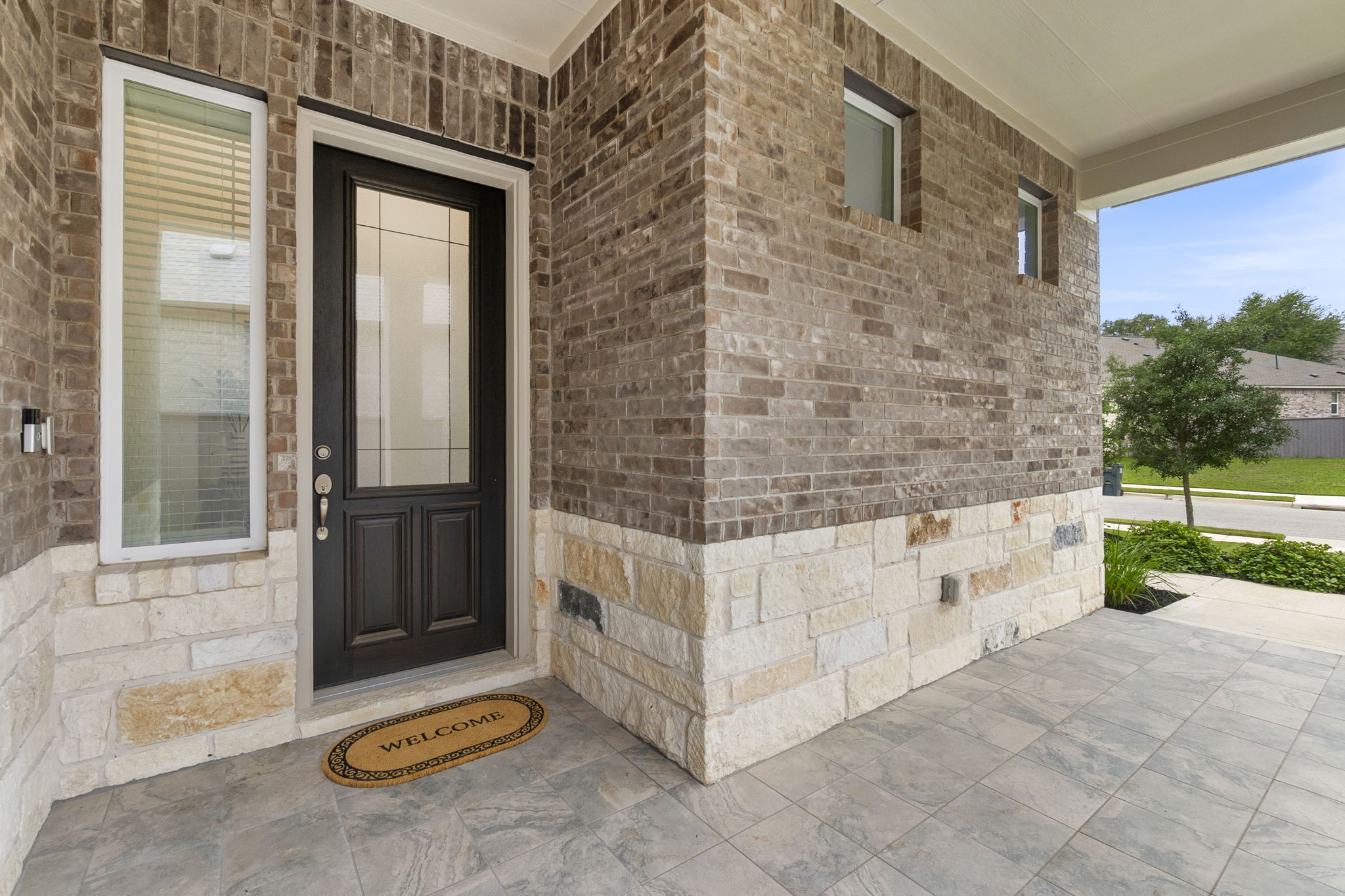 460 Constitution Way Kyle, TX 78640 - Photo 5 of 40 Exterior featuring a dark wood-finish entry door with glass inserts, flanked by a side light window with horizontal blinds