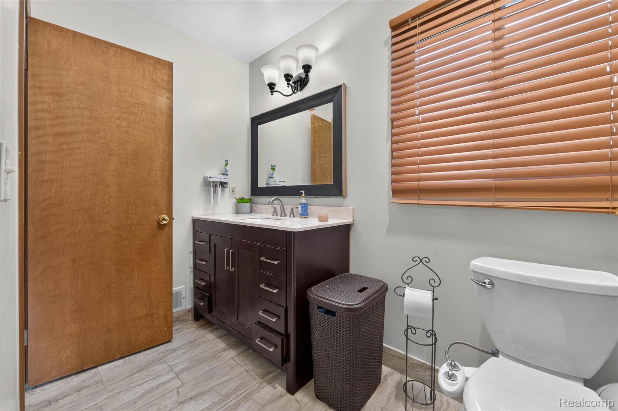46362 Springhill Drive Utica, MI 48317 - Photo 28 of 59 Bathroom featuring a dark wood-finish vanity with a light countertop, a rectangular mirror, and a three-light fixture