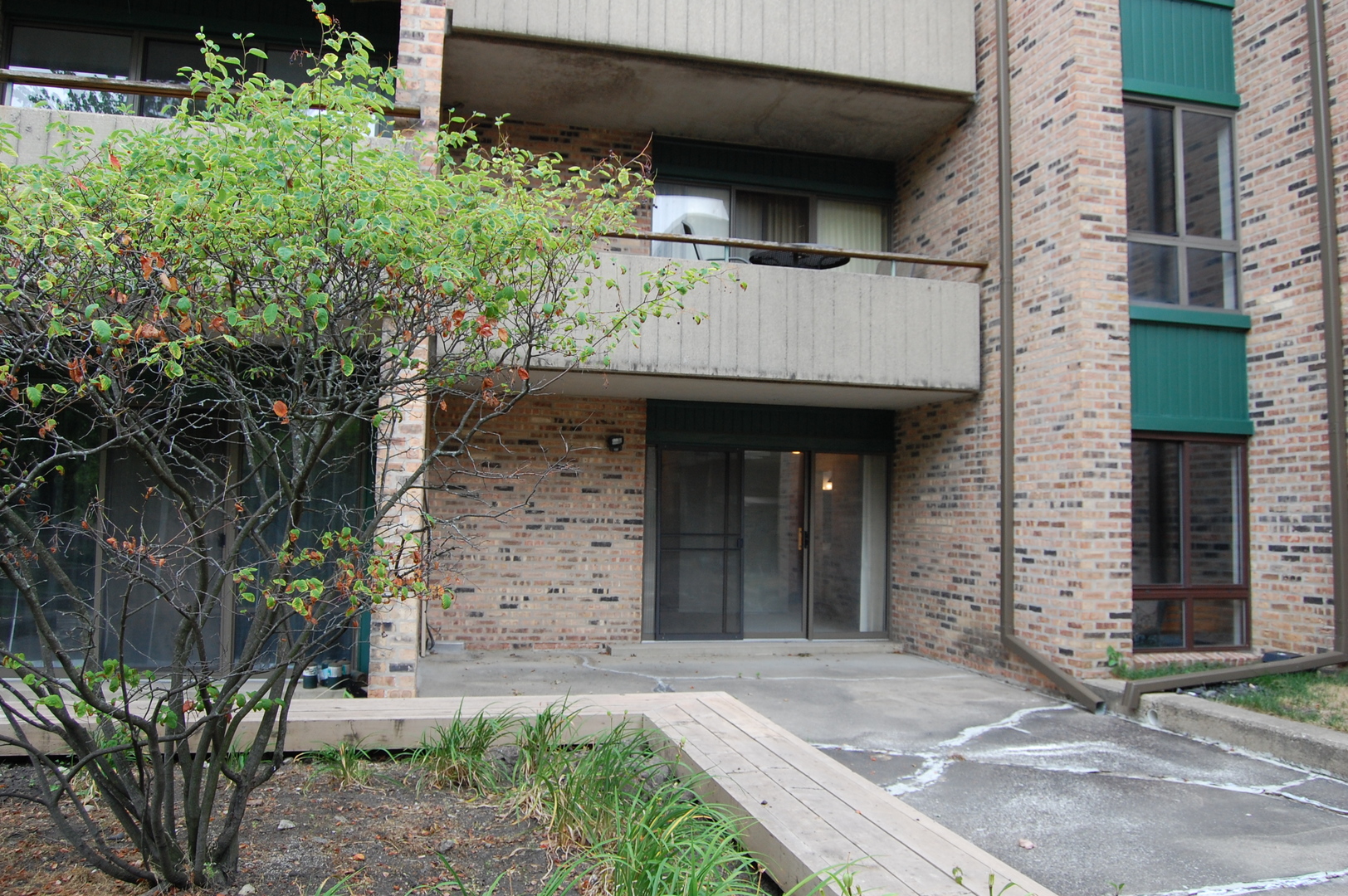 1919 Prairie Square, Unit 102 Schaumburg, IL 60173 - Photo 22 of 25 a view of a brick house with plants and large tree