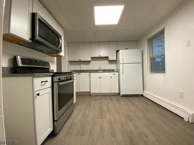 a kitchen with stainless steel appliances a stove a microwave and white cabinets