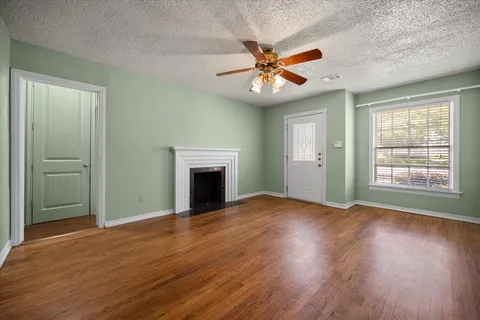 an empty room with wooden floor fan and windows
